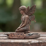 Bronze fairy figurine with 'Grateful' plaque on a wooden surface