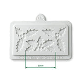 White silicone baking mold with holly leaf patterns, featuring a 50mm dimension marker overlay and a hanging loop at the top.