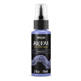A bottle of Americana BLOOM Textured Paint in the shade 'Bloomed Violet'. The 2 fl oz spray bottle has a black label with purple paint texture graphics and a clear spray cap, shown on a white background with a soft shadow.