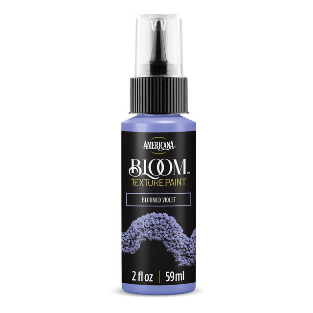 A bottle of Americana BLOOM Textured Paint in the shade 'Bloomed Violet'. The 2 fl oz spray bottle has a black label with purple paint texture graphics and a clear spray cap, shown on a white background with a soft shadow.