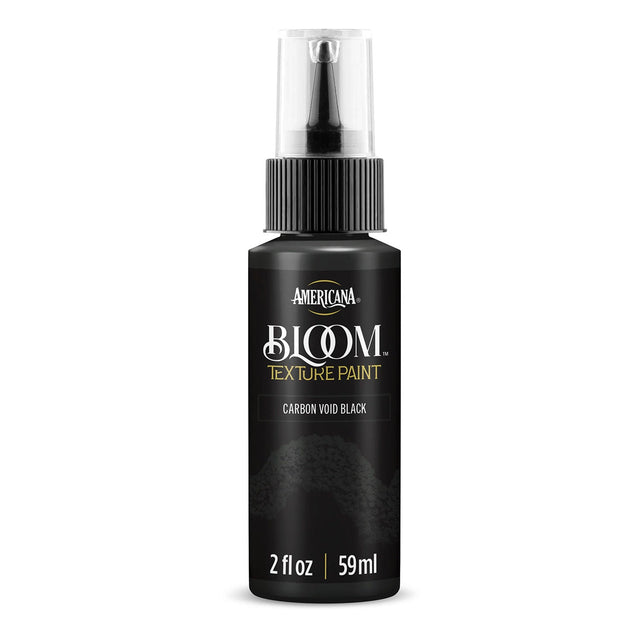 A bottle of Americana BLOOM Texture Paint in the color Carbon Void Black, featuring a black body, clear spray cap, and gold and white lettering on a white background.