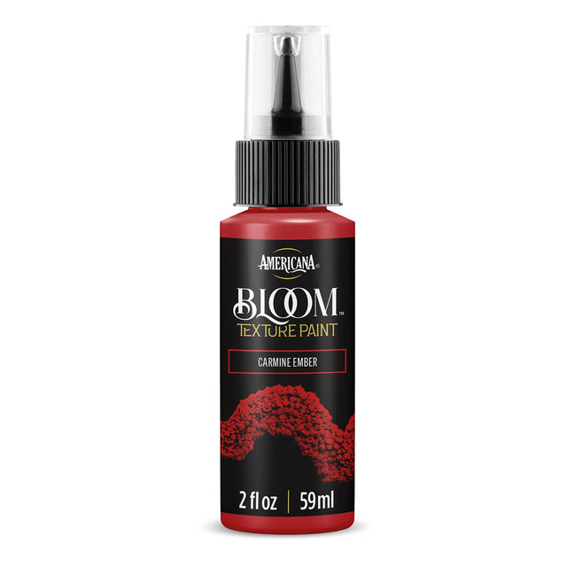 A bottle of Americana BLOOM Textured Paint in the shade Carmine Ember, featuring a black label with red paint splatter graphics and a clear spray cap, set against a plain white background.