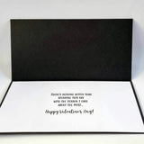 A black and white pop-up greeting card shown open, with a black back panel and a white front panel printed with the message, 'There's nothing better than spending this day with the person I care about the most.