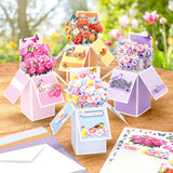 Colorful floral pop-up cards on a wooden surface with a blurred garden background