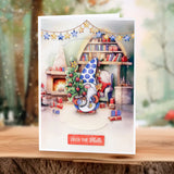 Christmas-themed greeting card with a gnome, tree, and fireplace on a wooden surface.