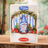 Christmas card with a gnome, wreath, and festive text on a wooden surface.