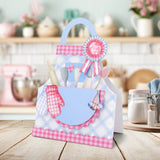 Baby shower gift basket with utensils and a baby bib on a kitchen counter.