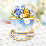 Decorative teacup with flowers and a spoon on a wooden surface