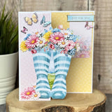 Greeting card with striped socks and flowers on a wooden surface