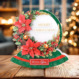 Decorative Christmas card with poinsettias and mistletoe on a wooden surface.