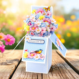 Decorative card with floral design and butterfly on a wooden surface with blurred flowers in the background