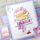 A colorful handmade birthday card featuring a 3D-style layered cake with candles, bows, strawberries, and decorative borders, shown alongside matching card elements on a light textured background.