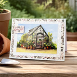 Greeting card with a greenhouse illustration and 'Have a Great Day' message on a wooden surface with plants.