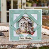 Greeting card with a garden shed and plants design, featuring 'Happy Birthday' text, on a rustic wooden surface.