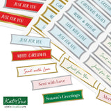 A collage of decorative holiday label stickers with phrases like 'Just for You,' 'Merry Christmas,' 'Sent with Love,' and 'Season's Greetings' in red, blue, pink, green, gold, and gray on a white background. The Katy Sue brand logo appears in the lower left corner.