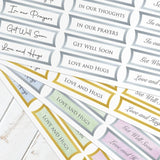 Collection of printed cards with messages like 'In our prayers' and 'Get Well Soon' on a wooden surface.