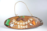 Wooden sign with 'Grandad's Shed' text and gardening tools on a white background