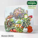 Colorful undersea scene with characters and sea creatures on a card, featuring Katy Sue Designs branding.