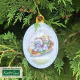 Decorative Christmas ornament with two snowmen on a tree branch, featuring Katy Sue branding.