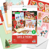 A festive card-making kit package labeled 'Santa & Friends Pop Up Christmas Card Making Kit' surrounded by sample holiday card designs and stickers, including Santa, penguins, gingerbread houses, elves, reindeer, and candy canes.