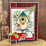 Christmas-themed card with a birdhouse design on a wooden surface.