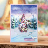 Christmas card with a snowy scene, tree, and 'Let it Snow' text on a wooden surface.