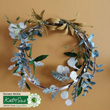 Floral wreath with green and white leaves on a beige background, featuring Katy Sue Design branding.