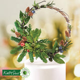 Decorative wreath with greenery and berries on a blurred background, featuring the Katy Sue Flower Co. logo.