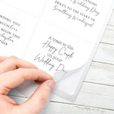 Hand holding a wedding card with text on a wooden surface