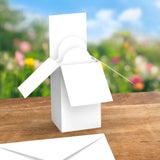 White windmill model on a wooden surface with a blurred natural background